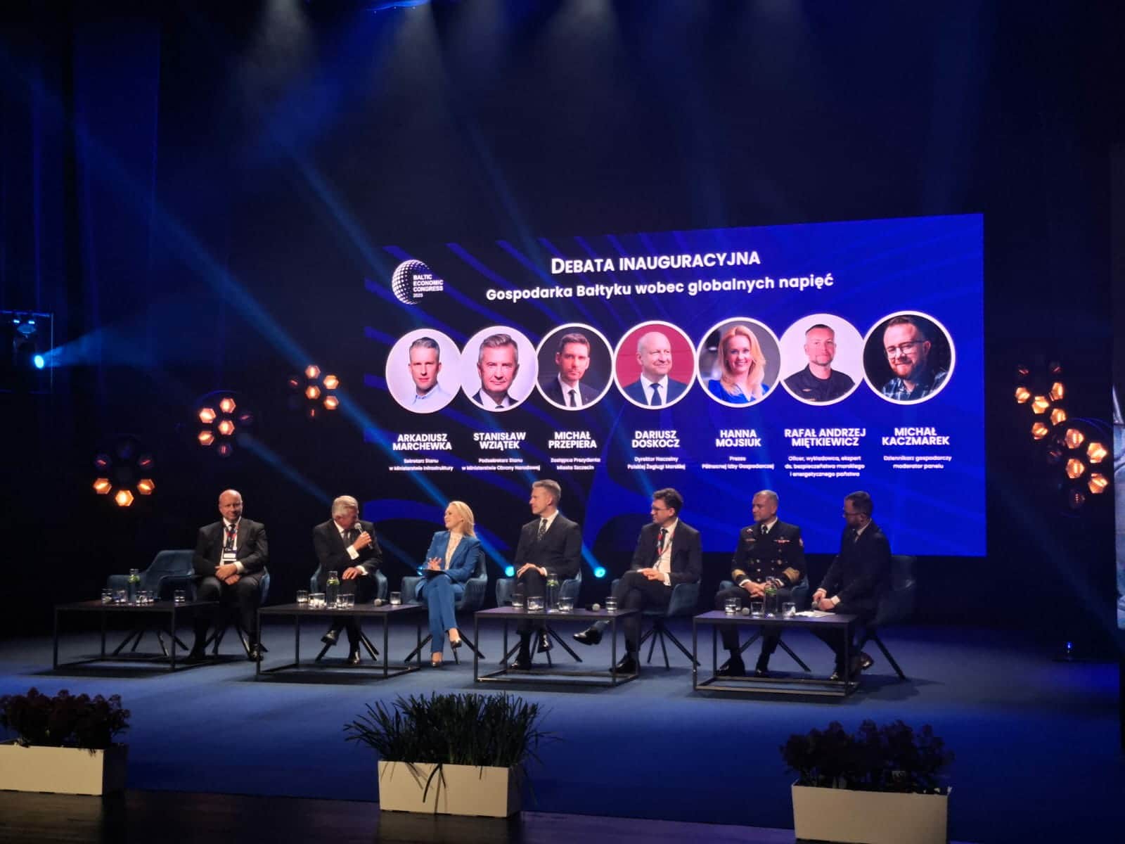 Debata inauguracyjna "Gospodarka Bałtyku wobec globalnych napięć". Na scenie siedzi panel ekspertów, a nad nimi wyświetlony jest slajd z nazwiskami i tytułami uczestników.